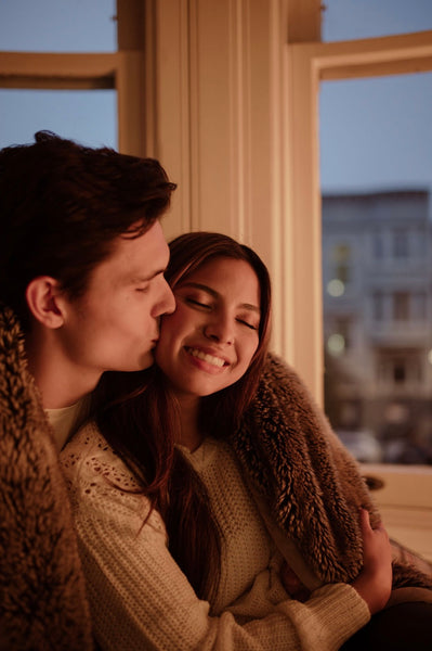 At Home Date Night Ideas: Couple sitting by the window in a blanket 