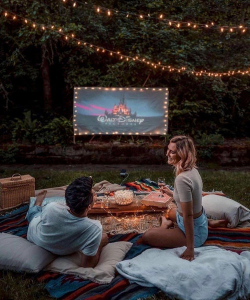 At Home Date Night Ideas: Couple watching a movie outside on a projector