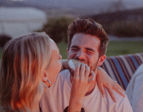 At Home Date Night Ideas: Girlfriend feeding her boyfriend a bite of smores