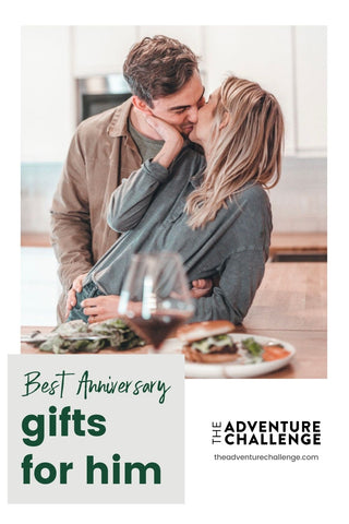 Couple sharing a kiss as they eat food and drink wine in their kitchen; image overlaid with text that reads Best Anniversary Gifts for Him