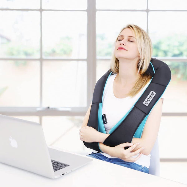 Lady leaning back as she wears the heated neck massager with her Macbook in front of her