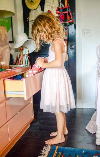 13 Calming Bedtime Activities for a More Peaceful Sleep for Your Children. Little girl in a pink dress picking out her clothes from her cabinet.