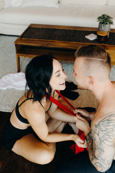 Creative, Romantic, and Fun Stay-at-Home Date Ideas for Couples: Couple sitting on the bed with the guy about to put a blindfold on the girl