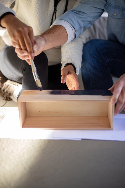 Close-up shot of a couple painting a wooden box together 