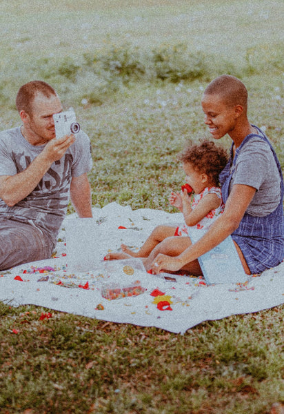 Family Connection: How to Bring Your Family Closer Together. Dad taking a photo of mom and baby while having an outdoor picnic.