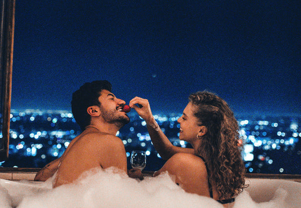 How The In Bed Book Helps Create Sexual Passion and Intimacy. Couple feeding each other berries in the bathtub with a view.