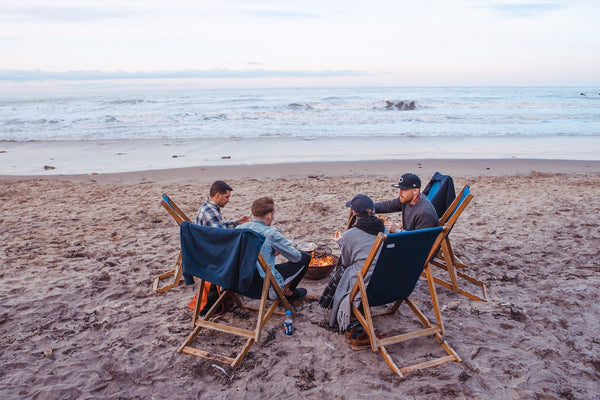 Group of guy friends sitting around a fire on the beach