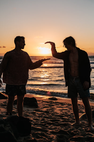 Silhouette of two guys standing by the beach and giving each other a high five