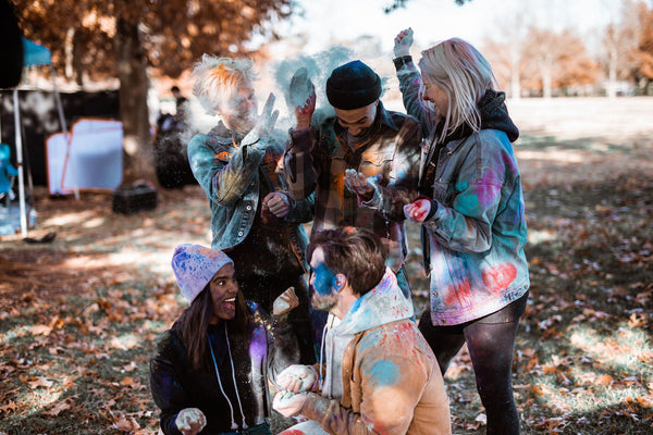 A group of five friends having fun with powdered paint in autumn