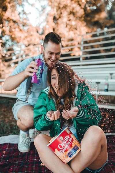 A girl smiles as her boyfriend pours nerds candy over her head