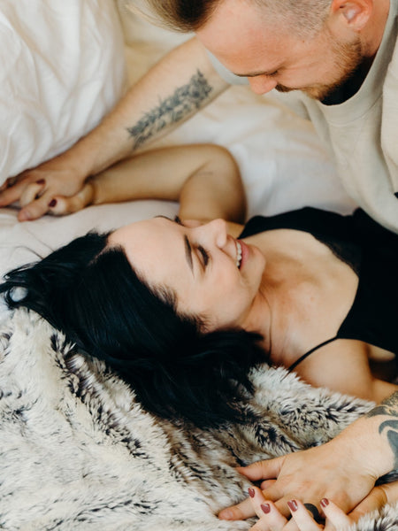 How to Last Longer in Bed with Your Loved One: Guy playfully pinning his girlfriend down on bed as they smile.