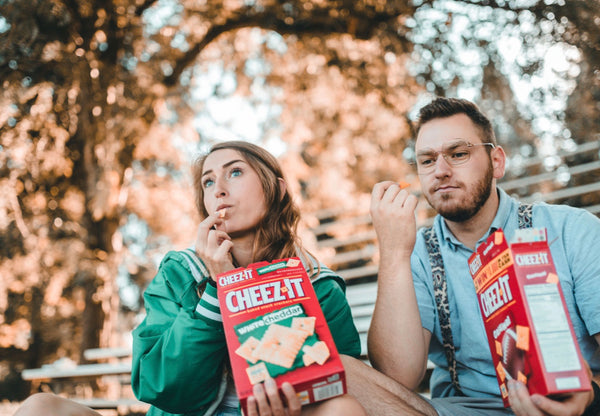 A couple sit together while eating out of boxes of Cheez-its