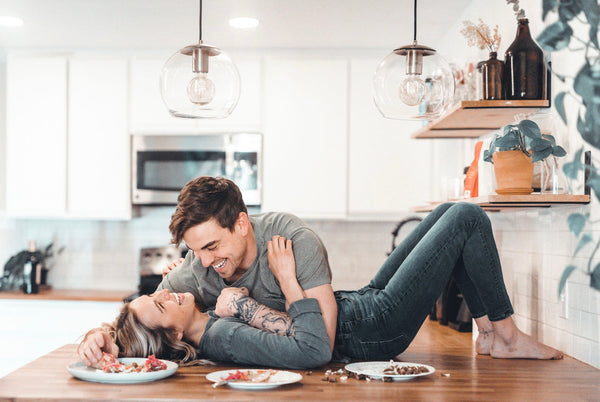 Couple sharing a laugh with the girl laying on the kitchen counter and the guy holding her down