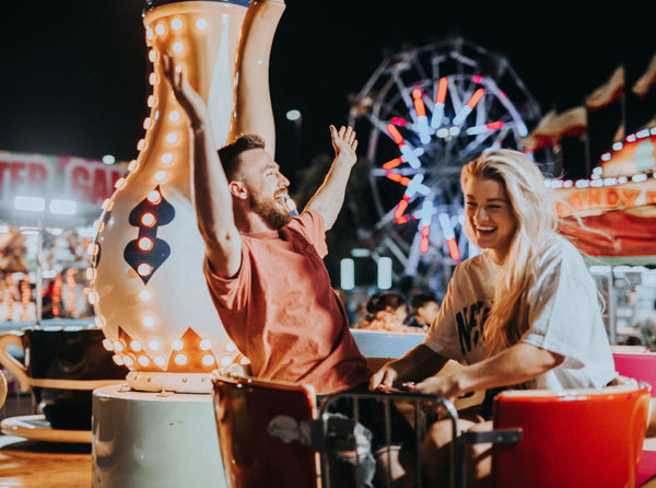 A couple smiling and laughing while on a carnival ride together.