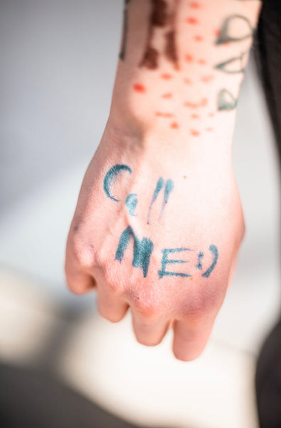 An image of a hand that has "Call Me :)" written on it