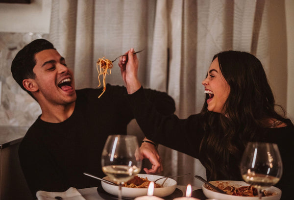 Image of a couple laughing together as they eat spaghetti