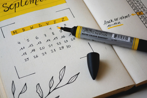The Ultimate Back to School List for 2021. Close up photo of a personal calendar for September with a yellow highlighter resting on the page. 