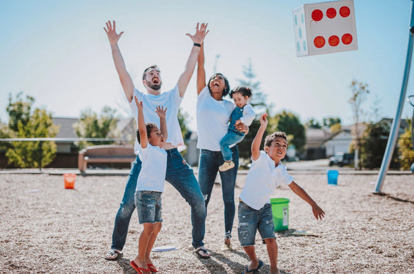 A family smiles and celebrates while standing at the playground during their summer adventures.