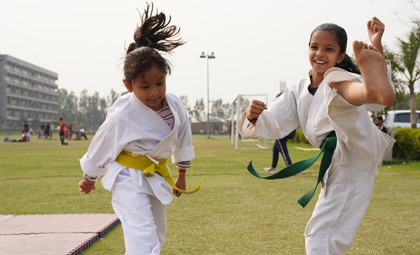 Two girls warming up for their karate classes at an outdoor park