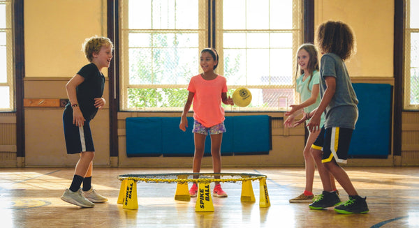 Why After School Activities Are so Important For Kids (And You!). Four kids playing a ball game together in a gymnasium.