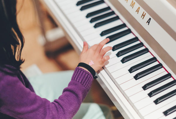  Why After School Activities Are so Important For Kids (And You!). Girl wearing a purple sweater playing the piano.