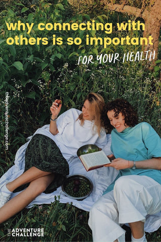 Two friends lay on a blanket while reading and laughing together; image overlaid with text that reads Why Connecting With Others is so important for your health
