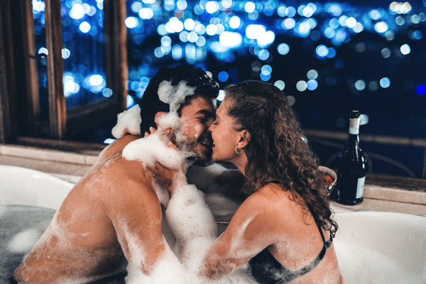 50 Items for Your Sexual Bucket List: Couple in bubble bath with city view.