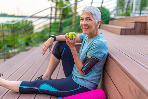 Older woman eating an apple after a workout