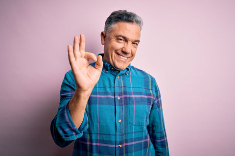 Middle age handsome grey-haired man wearing casual shirt over isolated pink background smiling positive doing ok sign with hand and fingers. Successful expression.