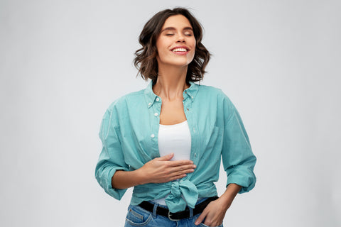 digestion, eating people concept - happy smiling full young woman in turquoise shirt touching her tummy over grey background