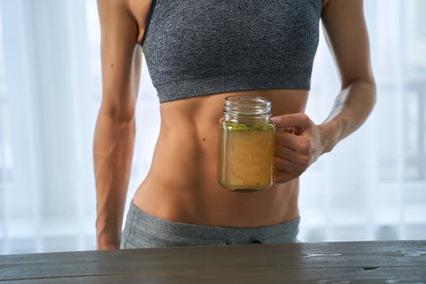 Woman drinking a hot drink. Sporty woman with a cup bone broth.