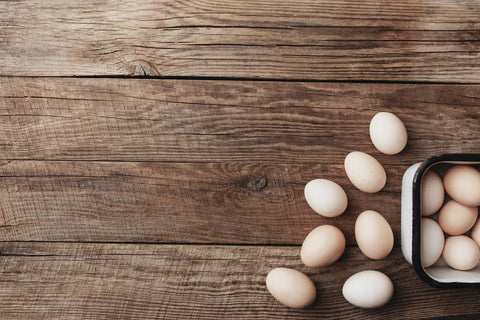 Organic chicken eggs in metal box on wooden background in a row. Organic household concept with eggs from free-range and pasture raised hens