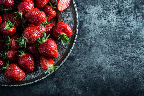 Top of view fresh strawberry in wrought plate on concrete board.