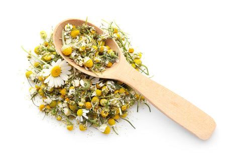 chamomile flowers ground on white backdrop with spoon