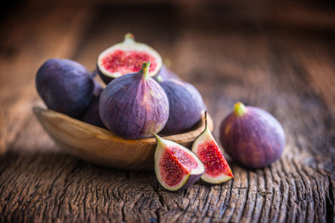 A few figs in a bowl on an old wooden background.