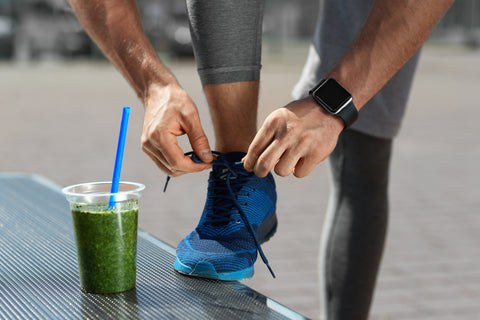Nutrition. Male Legs With Healthy Detox Drink At Outdoor Workout. Close Up Of Green Vegetable Smoothie In Plastic Cup, Shoe And Smart Watch On Hand. Healthy Lifestyle. High Resolution.