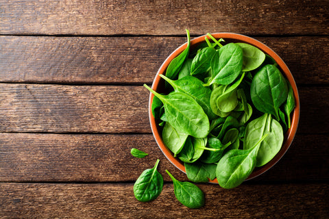 Spinach in bowl on wood backdrop