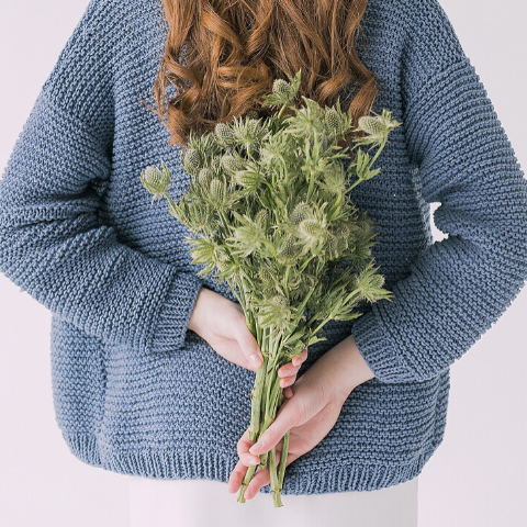 Woman holding bunch of flowers behind back