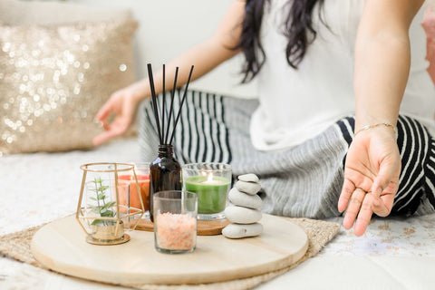 Woman in white tank top in a meditation pose with candles