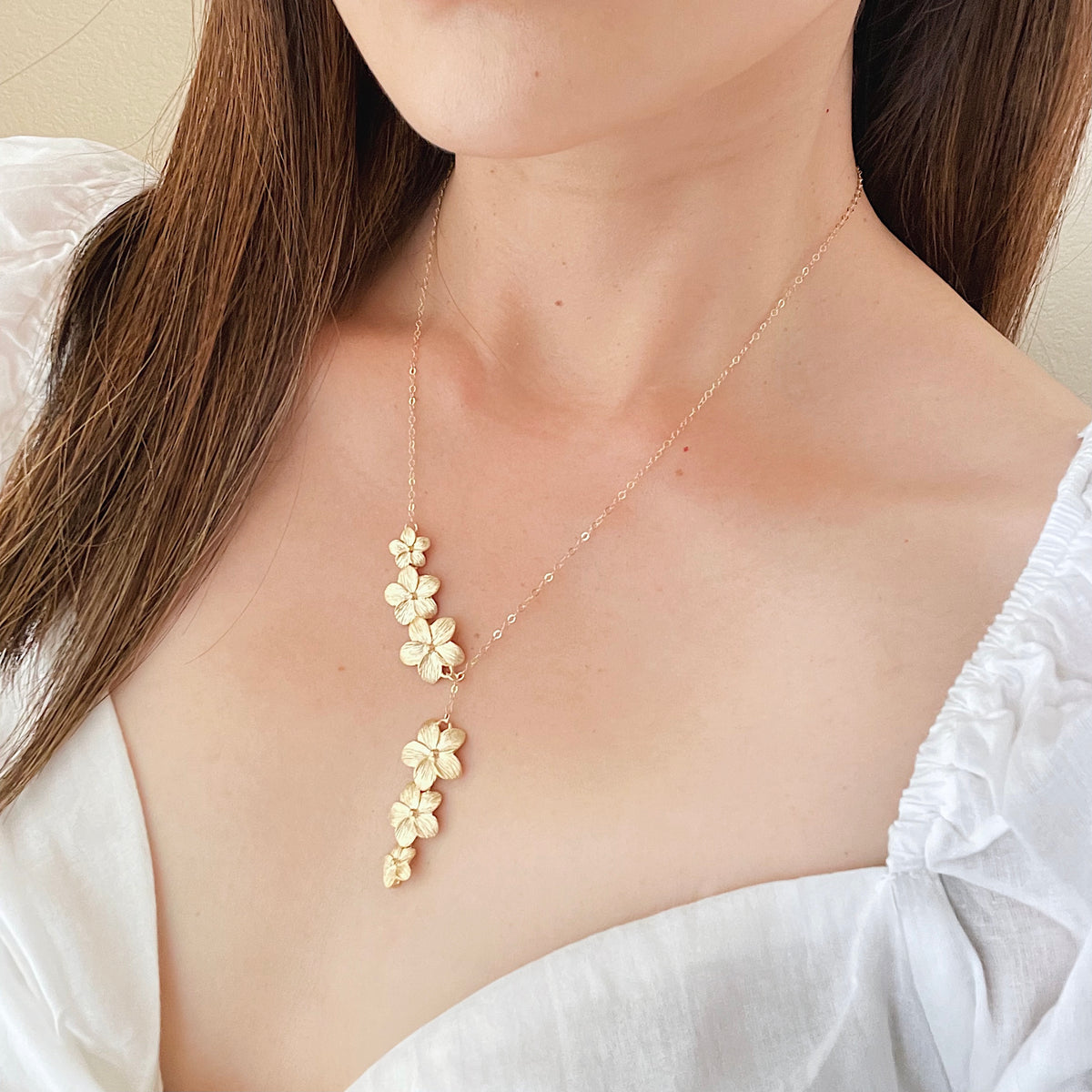 Woman wearing gold plumeria lariat necklace