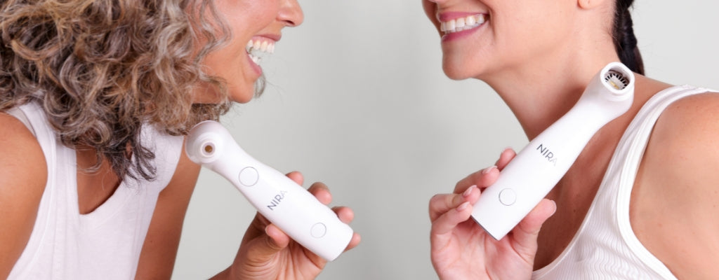 Two women with smooth, healthy skin holding the NIRA lasers