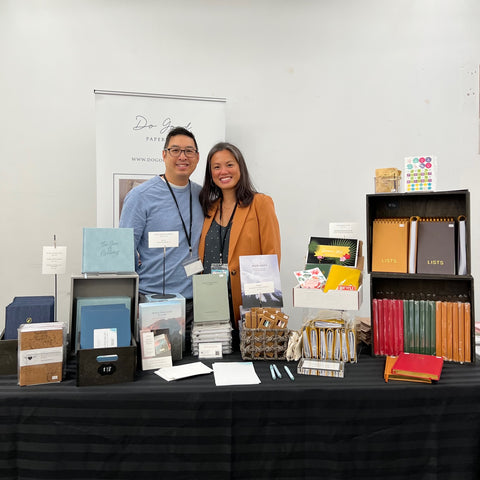 Leslie and Richard standing behind table filled with journals at Toronto Stationery Show