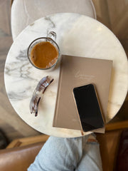 Planner, phone, coffee and sunglasses on a marble table