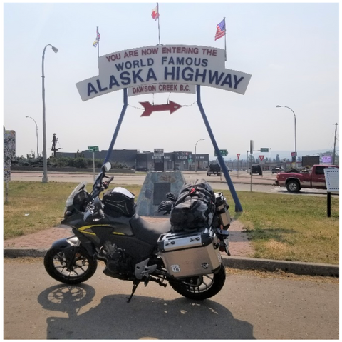 Motorcycle in front of the sign marking the Alaska Highway