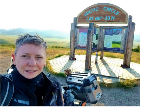 Ande and motorcycle infront of the sign for the Arctic Circle