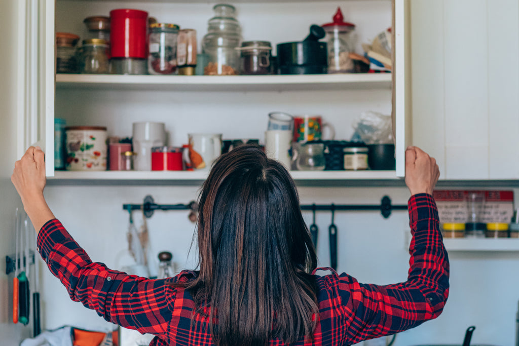 woman looking in messy cabinet