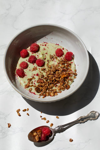 Matcha smoothie breakfast with granola and raspberries 