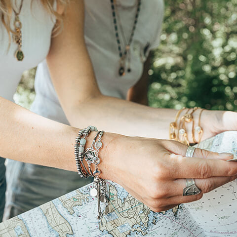 Women Wearing AIR AND ANCHOR jewelry while looking at a map preparing for an adventure.