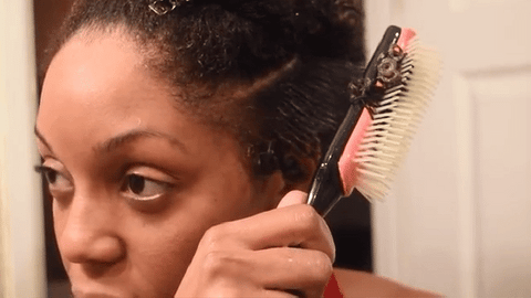 woman defining curls with Denman brush