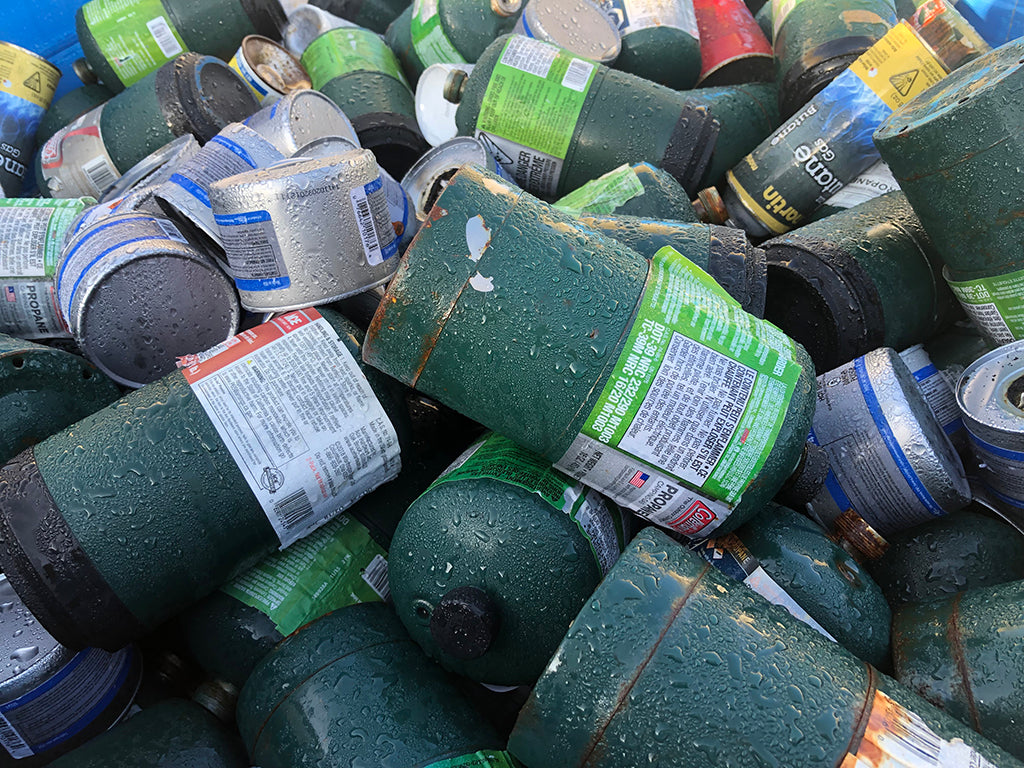 Single use green propane bottles in trash